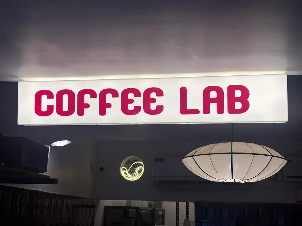A red Coffee Lab sign and glowing paper lantern